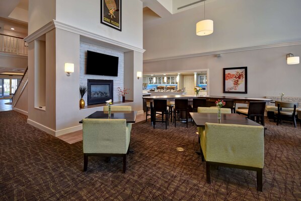 A hotel lobby with a fireplace, seating area, and a bar. - Homewood Suites by Hilton Philadelphia Great Valley (Malvern)