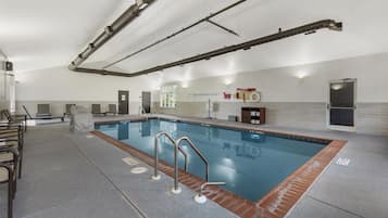 Una piscina con solárium de baldosas, barandillas metálicas y puesto de socorrista.