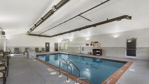 Una piscina con solárium de baldosas, barandillas metálicas y puesto de socorrista.