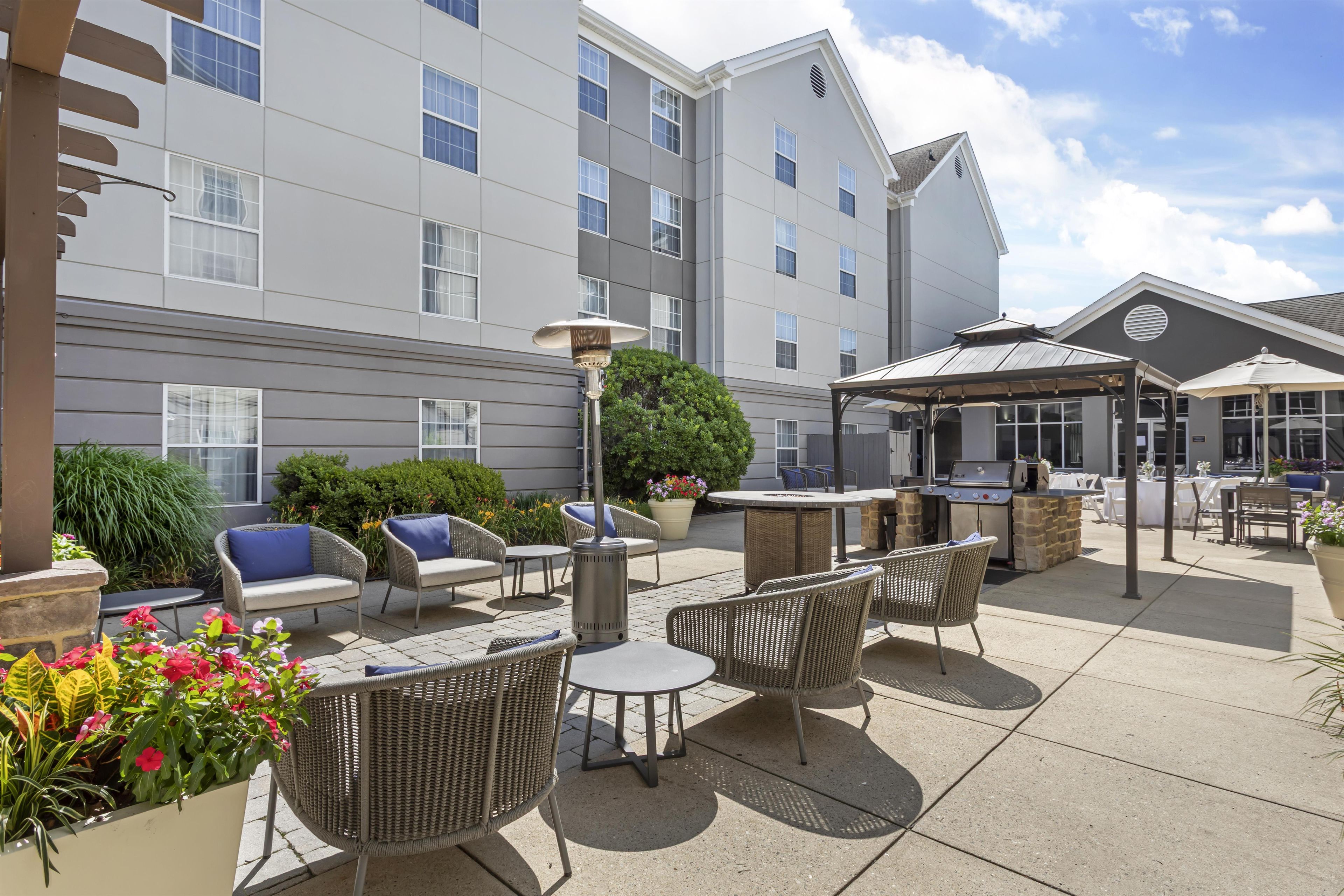 An outdoor patio area with wicker furniture, a barbecue grill, and a covered seating area.