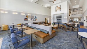 A spacious hotel lobby with a high ceiling, seating areas, and a dining space. - Homewood Suites by Hilton Philadelphia Great Valley (Malvern)