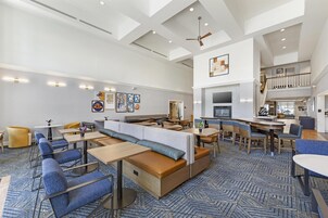 Un amplio vestíbulo de hotel con techo alto, zonas de estar y un espacio para comer.