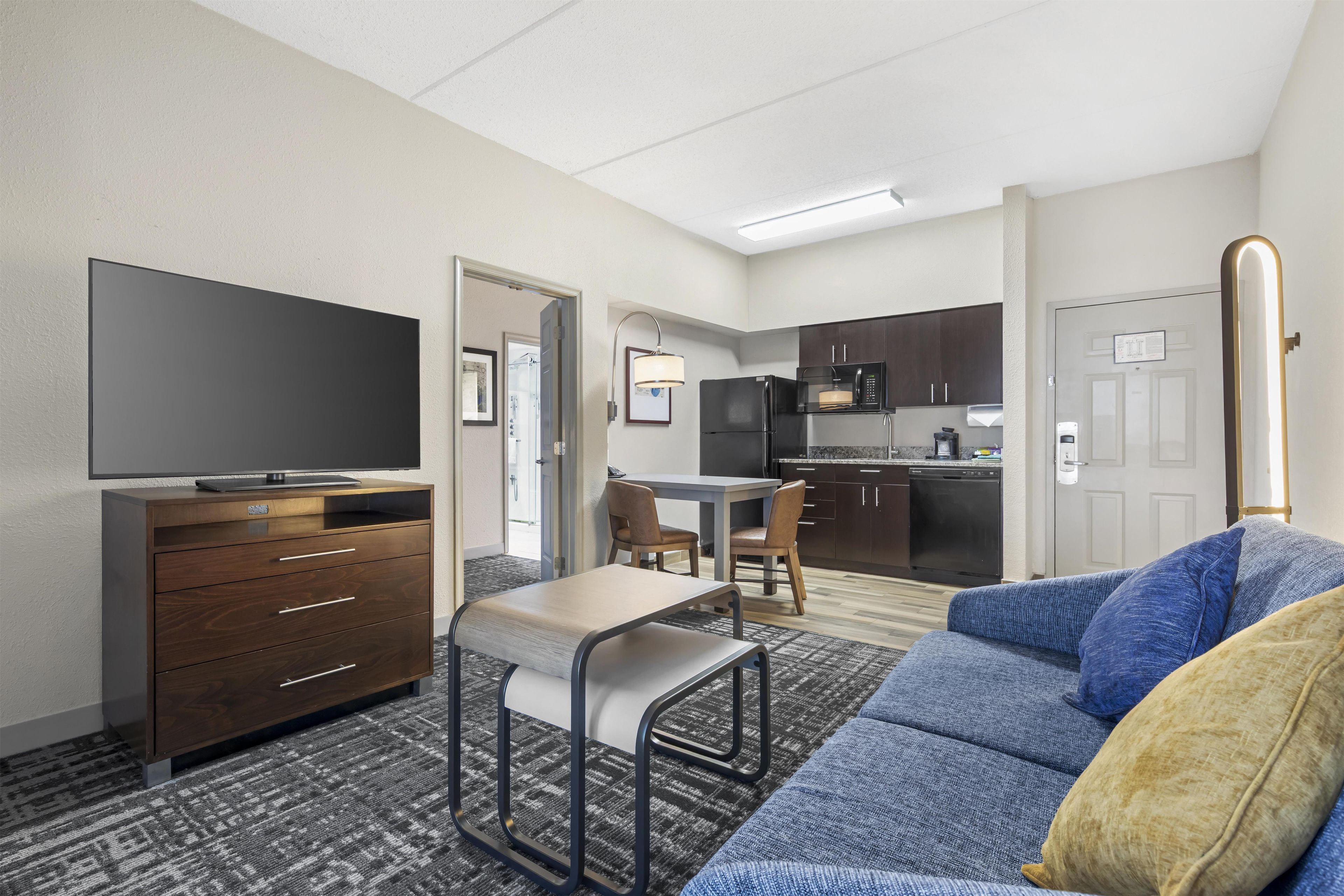 Un espacio habitable compacto con sofá, televisor, kitchenette y zona de comedor.