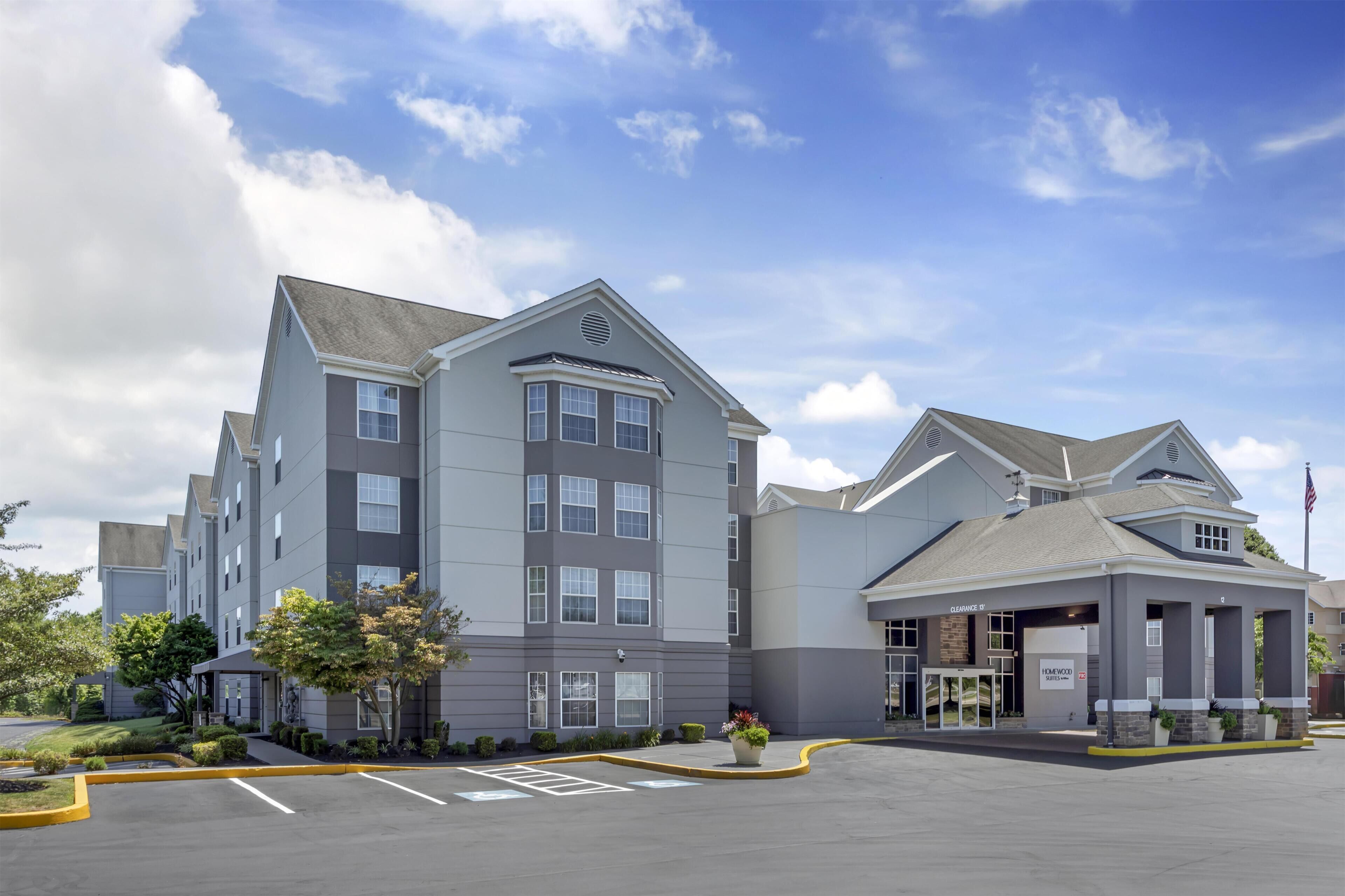 A multi-story hotel with a parking lot, a covered entrance, and a sign indicating 'Clearance 13''.