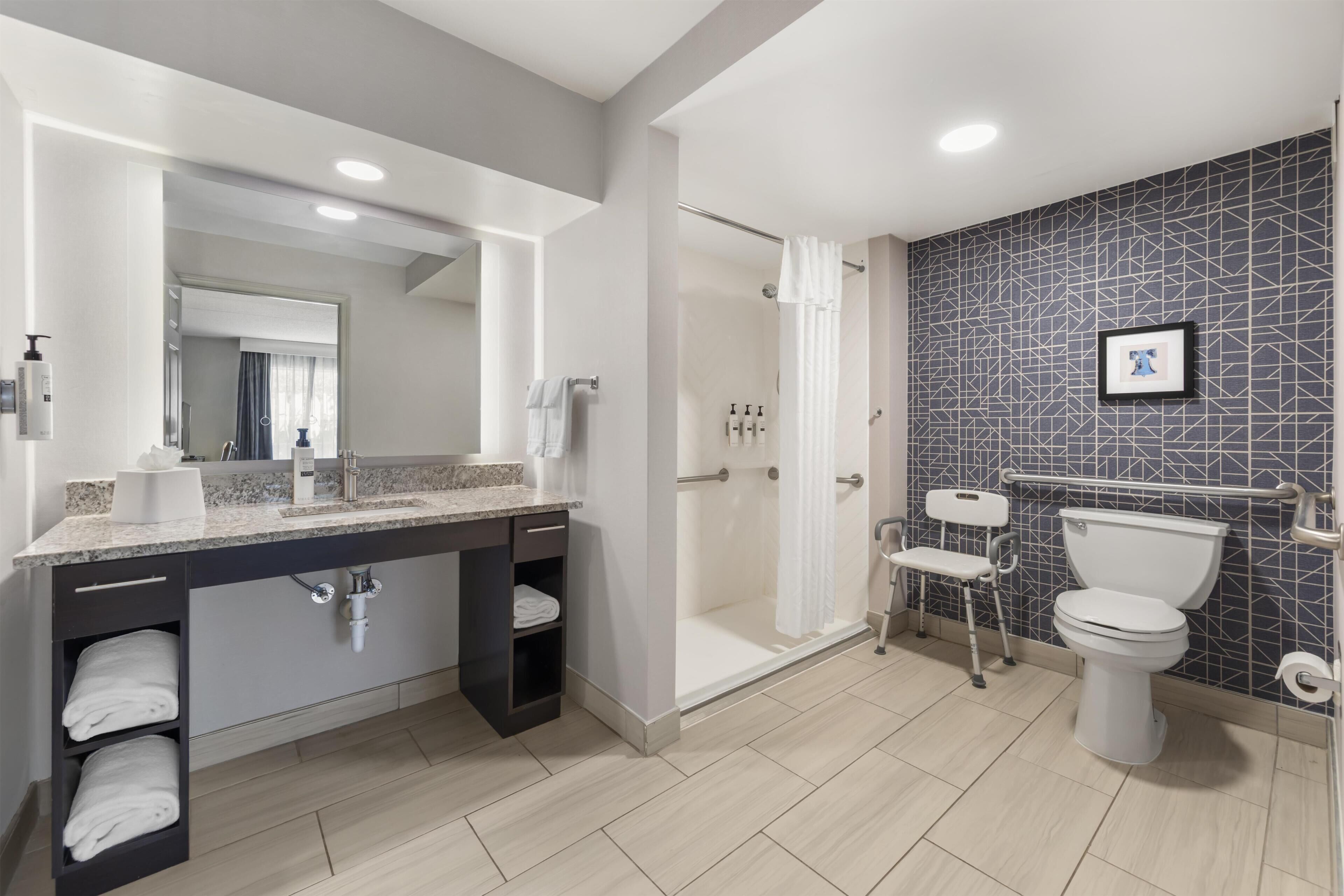 A modern bathroom with a shower, toilet, and sink.