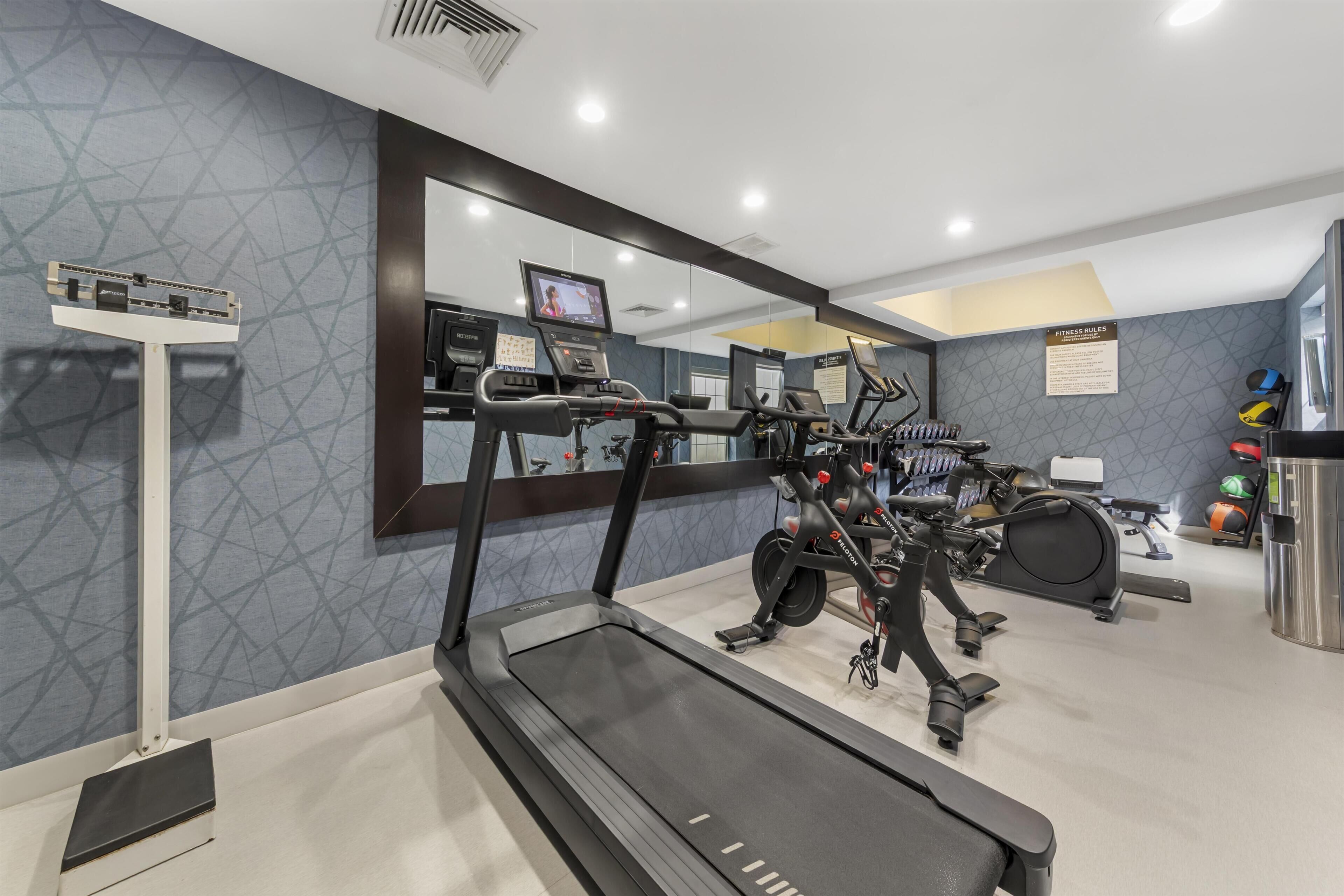 A gym with exercise equipment, a treadmill, and a mirrored wall.