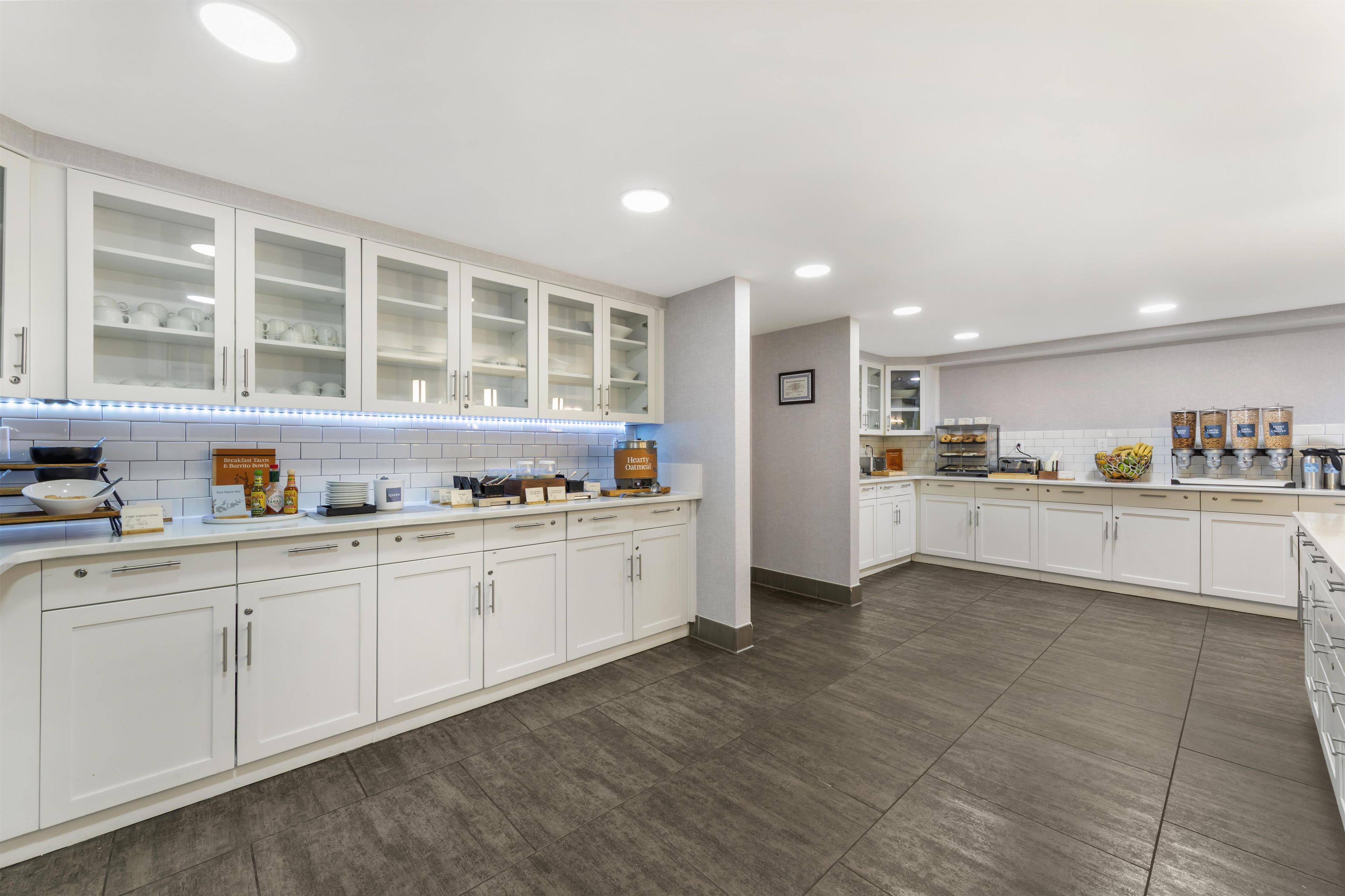 A modern kitchen with white cabinetry, a breakfast bar, and a breakfast bar sign.