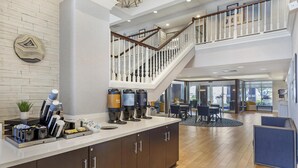 A hotel lobby with a coffee station, wooden flooring, and a staircase. - Homewood Suites by Hilton Philadelphia Great Valley (Malvern)