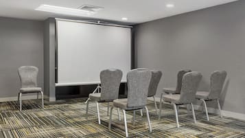 A conference room with a whiteboard, grey upholstered chairs, and patterned carpet.