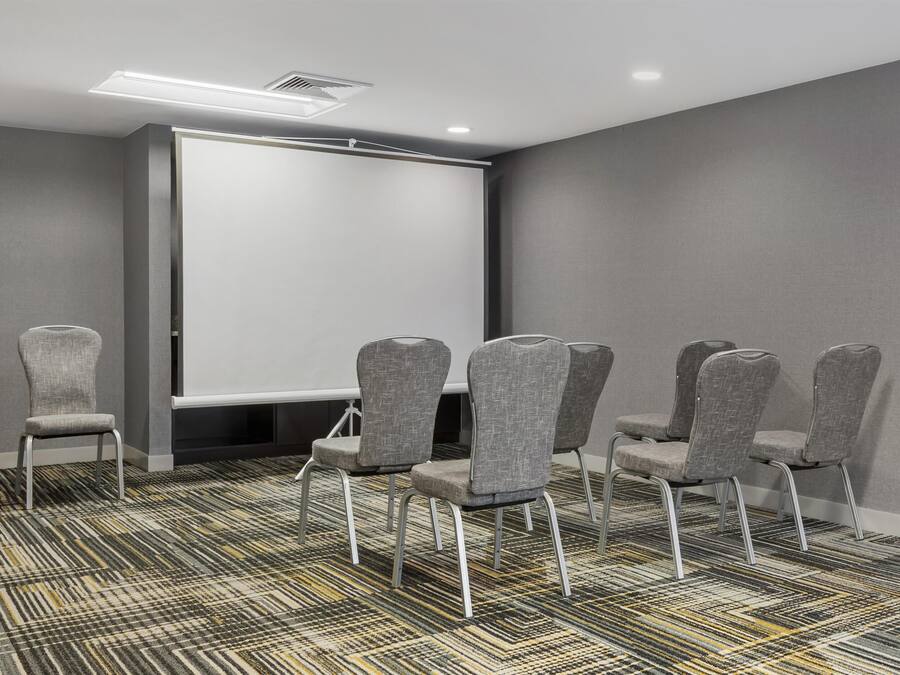 Un salón de conferencias con una pizarra, sillas tapizadas grises y alfombra estampada.