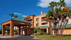 Ein Hotel mit überdachter Eingangsparte, Palmen und einem Schild für 'Courtyard by Marriott'.