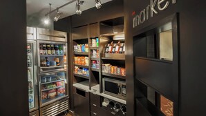 Eine helle, moderne Küchenzeile mit Kühlschrank, Mikrowelle und Regalen voller Snacks und Getränke.