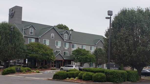 A multi-story hotel with a grey facade, multiple windows, and a parking lot in front. - Country Inn & Suites by Radisson, Rock Hill, SC (Rock Hill)