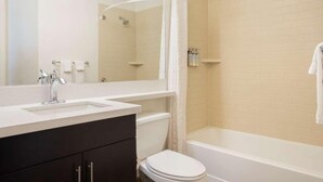 Une salle de bain avec un lavabo blanc, des toilettes, une baignoire et un rideau de douche.