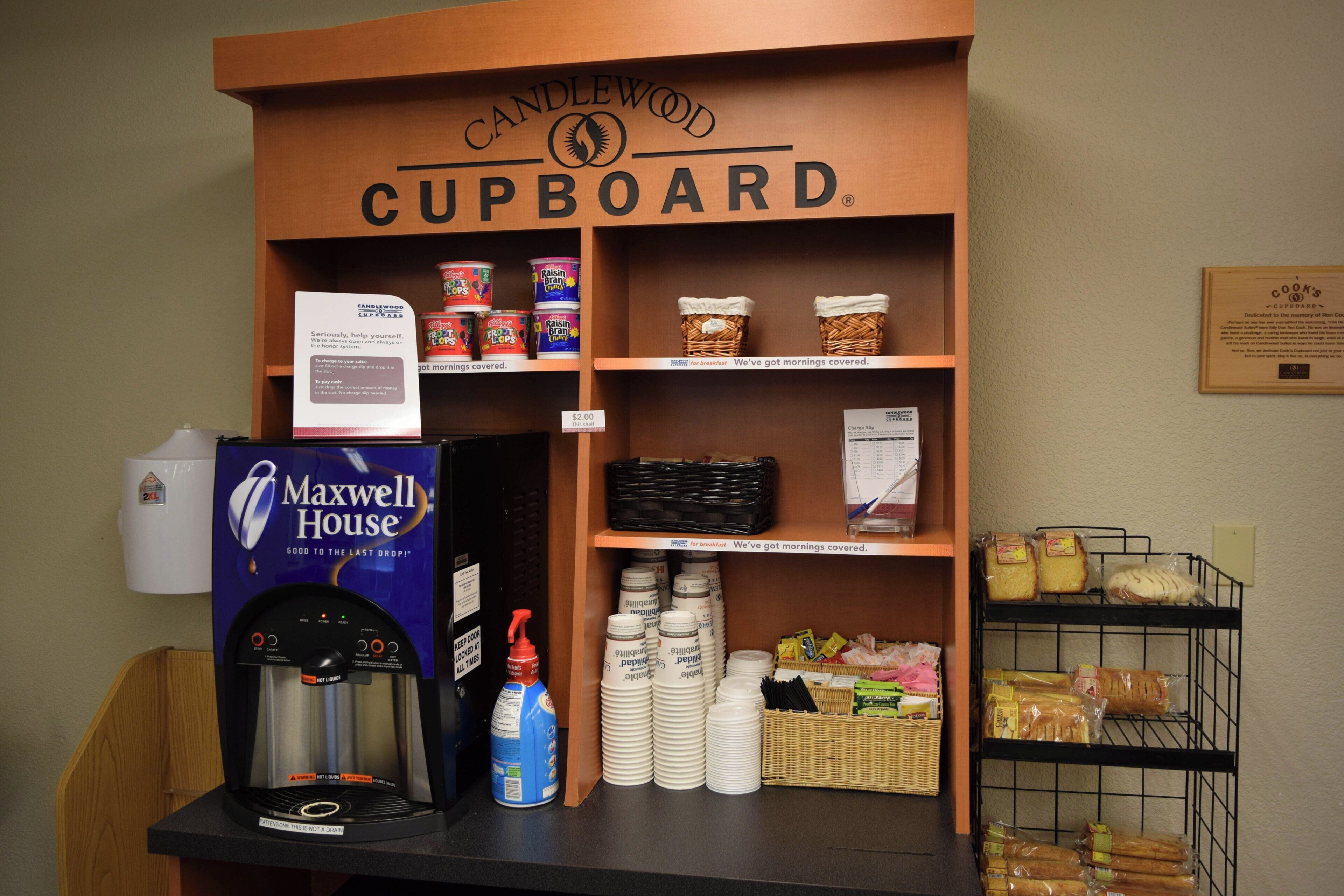 A kitchenette area with a coffee machine, a water dispenser, and a sign for the Candlewood Cupboard.