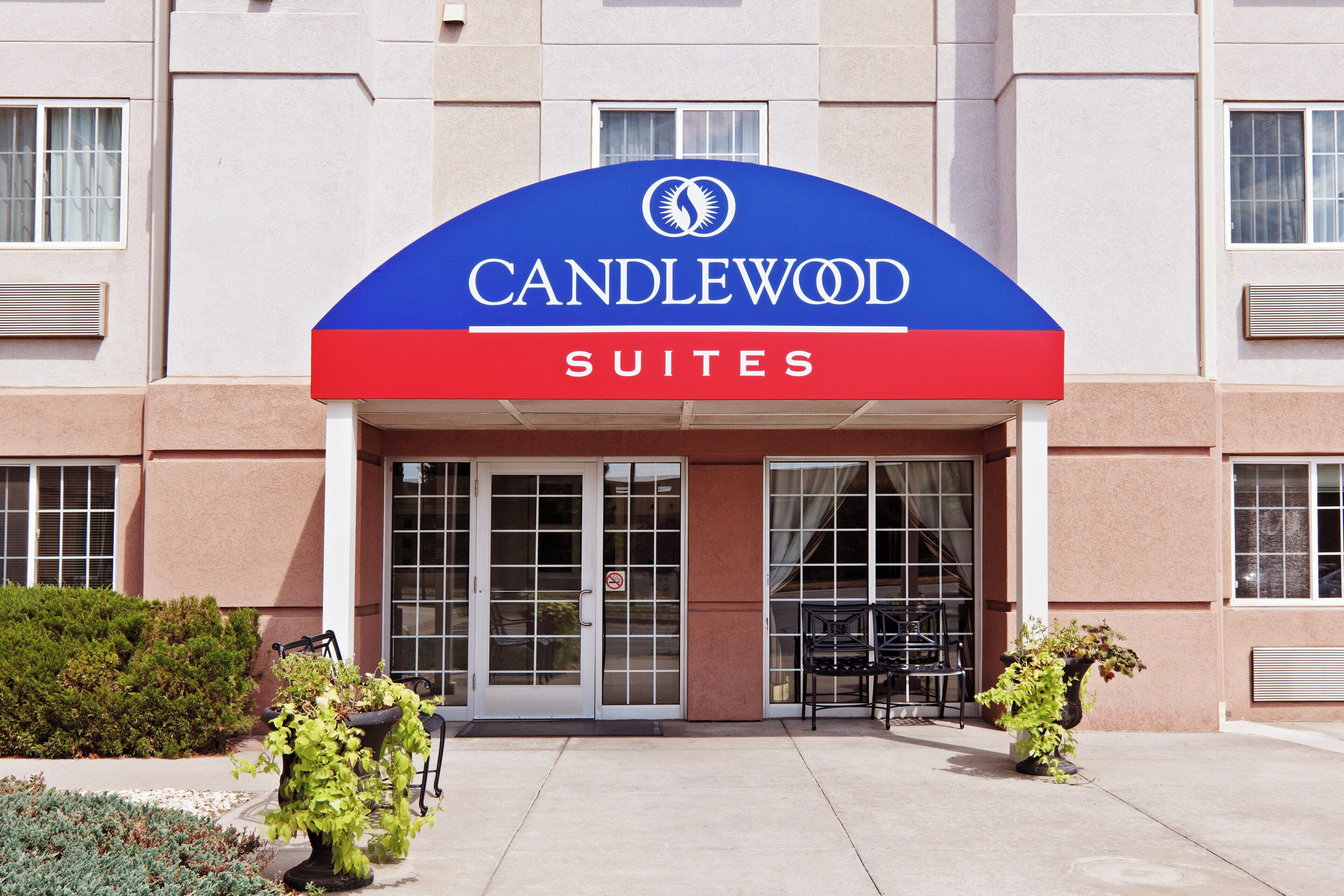 Entrada de un hotel con un cartel que dice 'CANDLEWOOD SUITES' y puerta de vidrio.