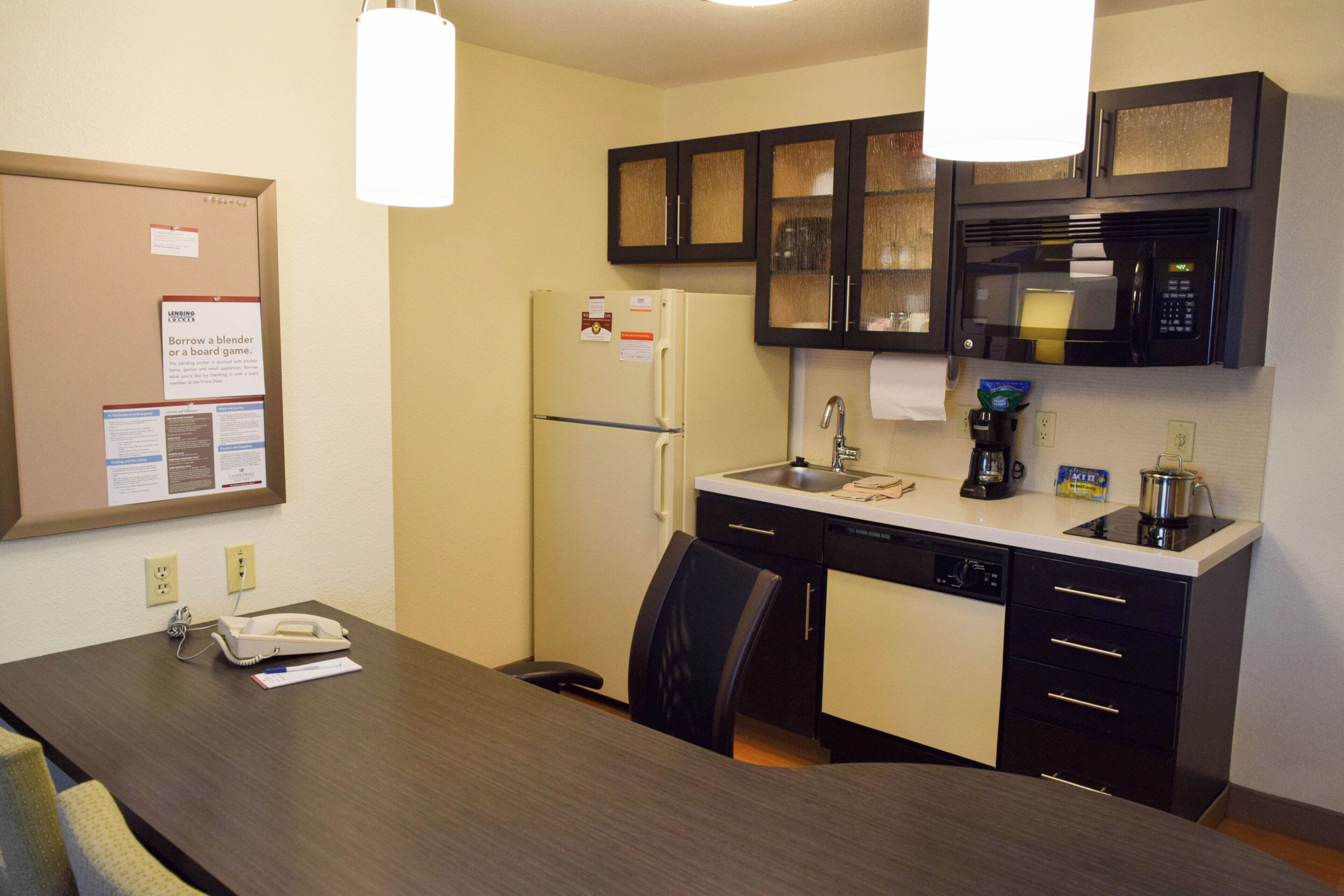 Cocina compacta con refrigerador, microondas, cafetera y una mesa de comedor con sillas.