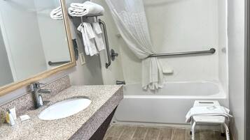 Un baño con lavamanos de encimera de granito, un espejo, ducha con puerta de cristal y un taburete pequeño.