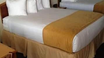 Two single beds with white linens and brown headboards, a nightstand with a lamp in between.