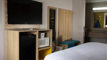 A hotel room with a bed, a television, a microwave, and a wardrobe.