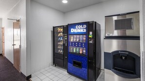 A hallway with a vending machine labeled "COLD DRINKS" and a Scotman branded refrigerator. - Motel 6 Bedford, TX - Fort Worth (Bedford)
