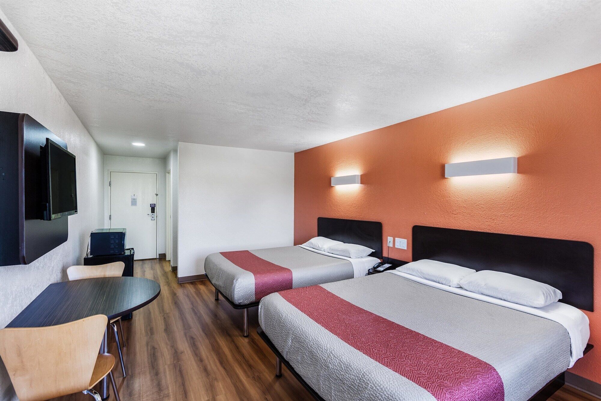 A hotel room with two beds, a desk, and a chair.