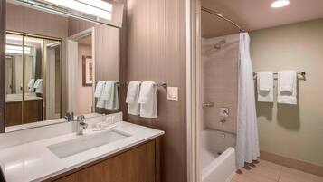 A modern bathroom with a large mirror, a sink, a shower, and a bathtub.