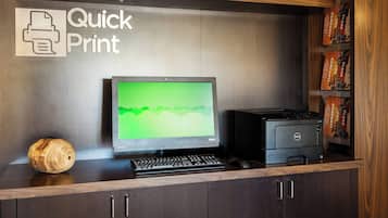 A desk with a computer, keyboard, and a printer. There is a sign above the desk that reads "Quick Print."