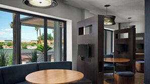 Een modern interieur met een bank, ronde tafels en een aan de muur bevestigde televisie.