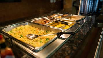 A buffet with various dishes, including a large tray of pasta garnished with herbs.