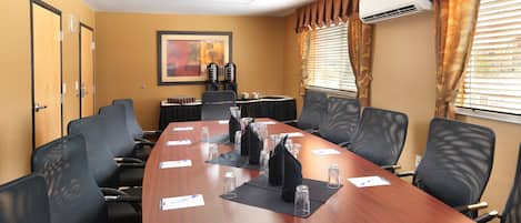 A conference room with a long table, chairs, and an air conditioning unit.