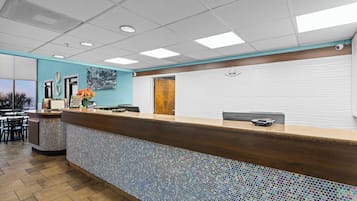 A reception area with a tiled mosaic counter, a wooden reception desk, a "Welcome" sign, and a view of the outside.