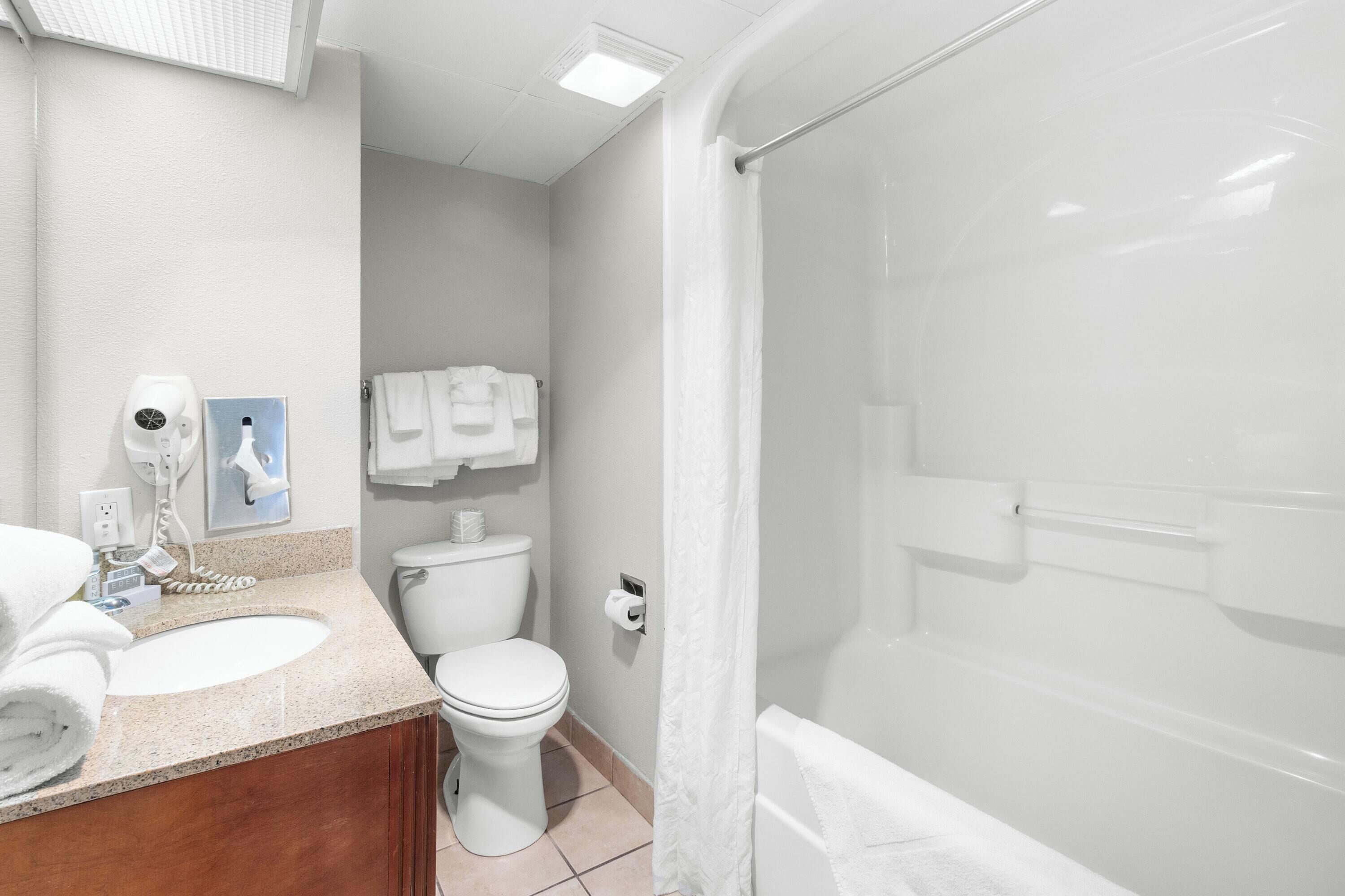 Un baño con lavamanos, inodoro y zona de ducha.