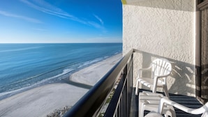 A balcony with a view of the beach and ocean.