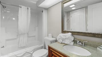 A bathroom with a bathtub, toilet, sink, and a large mirror.