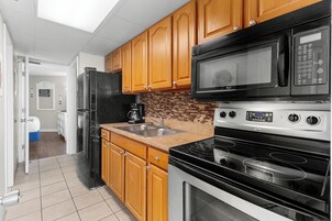 A kitchen with wooden cabinets, a black refrigerator, a microwave, a stove, and a sink.