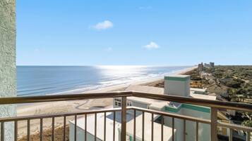 Un balcon donnant sur une plage et des immeubles.
