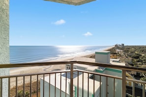 Un balcón con vista a la playa y edificios.
