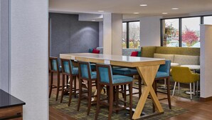 A modern hotel lobby with a bar area, seating, and large windows. - Hampton Inn Anchorage (Anchorage)
