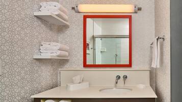 Un baño con lavamanos, espejo, toalleros y azulejos con diseño.