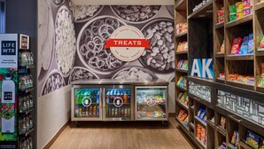 A store with a 'Treats' sign, refrigerated beverage dispensers, snack shelves, and a 'Life WTR' display. - Hampton Inn Anchorage (Anchorage)