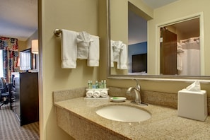 Une salle de bain d’hôtel avec un lavabo doté d’un plan de travail en granit, un miroir et un porte-serviettes sur lequel sont pliées des serviettes.