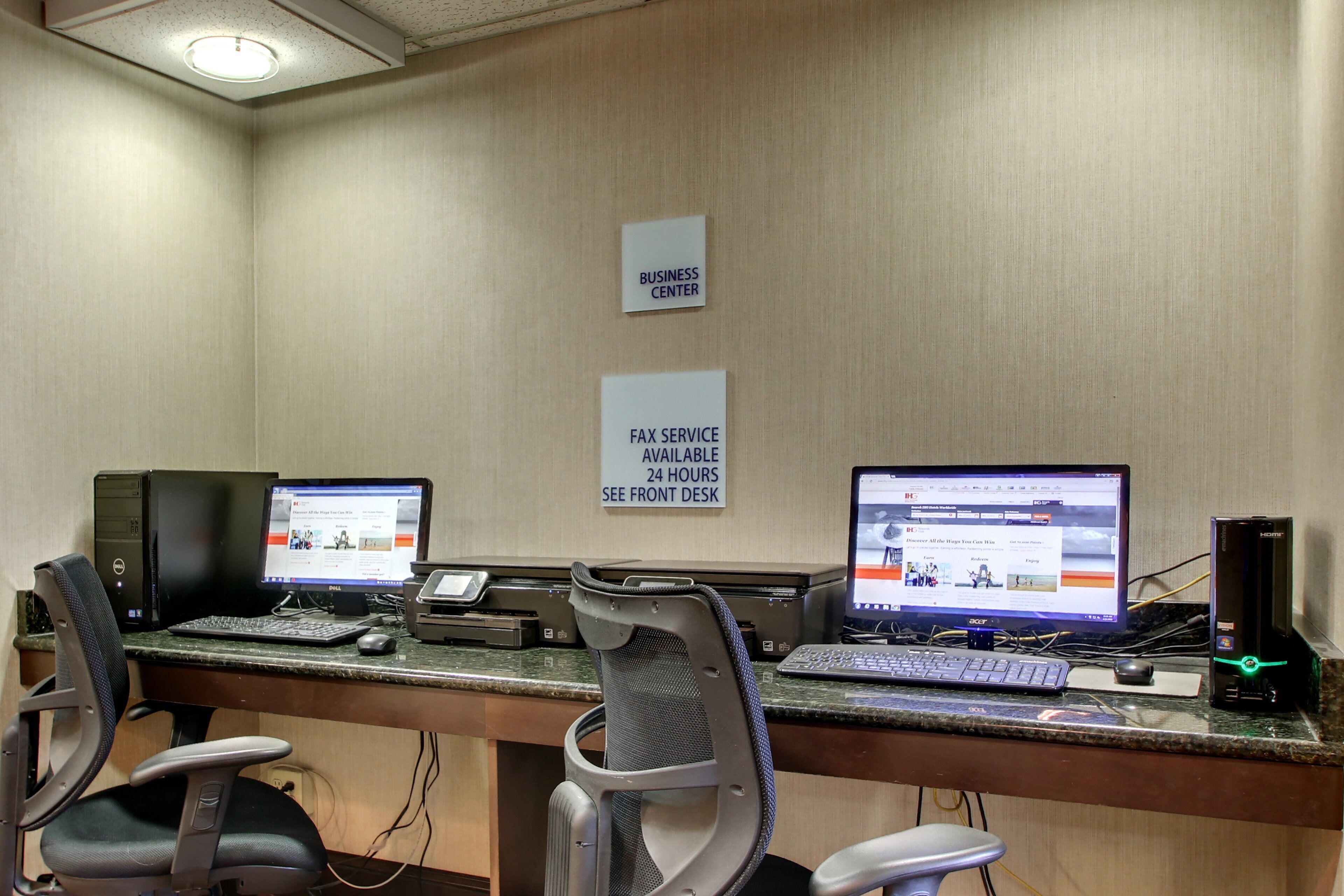 Centro de negocios con dos estaciones de trabajo de computadora, sillas y un letrero que indica servicio de fax.