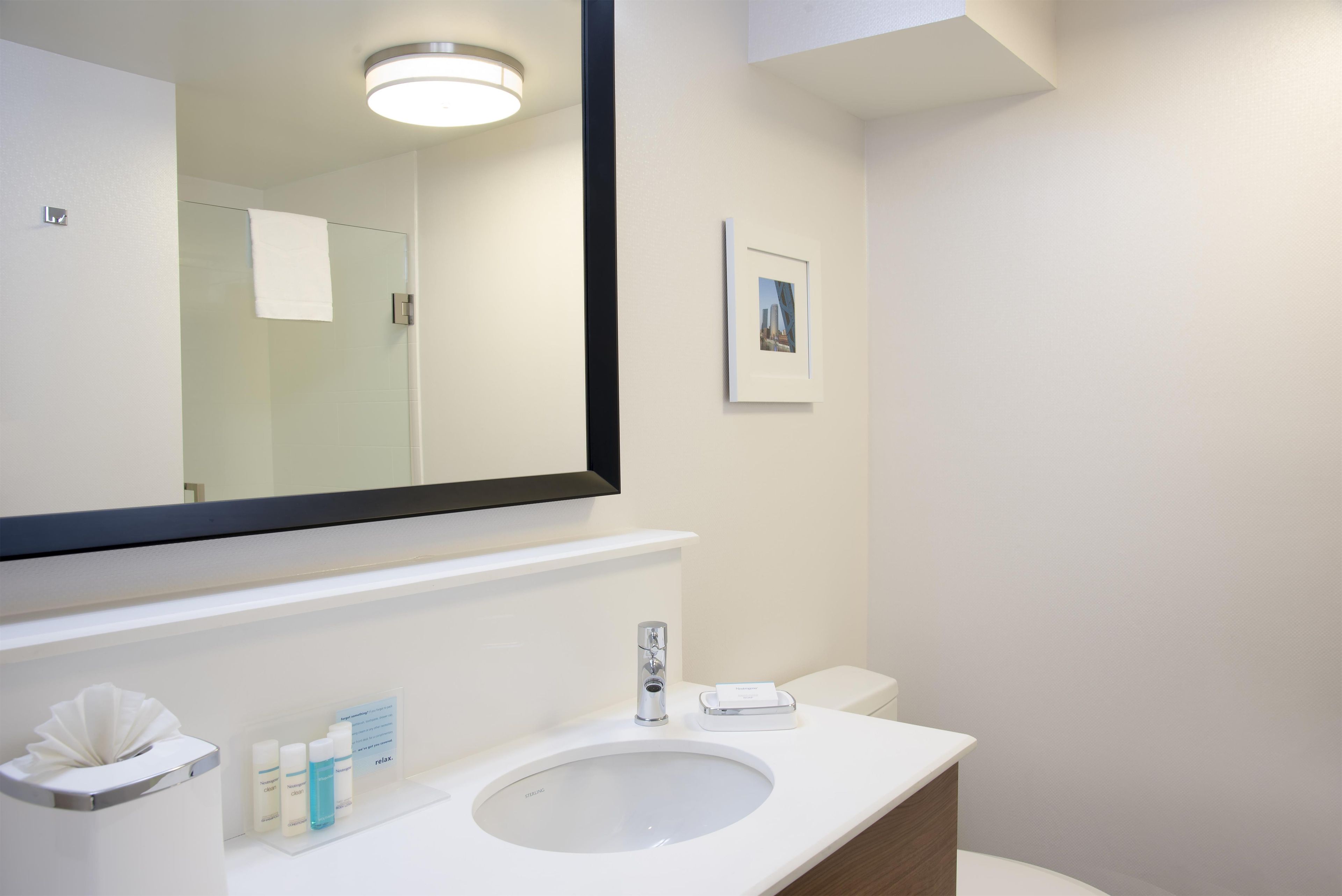 Un baño moderno con un espejo grande, un lavamanos y un inodoro.