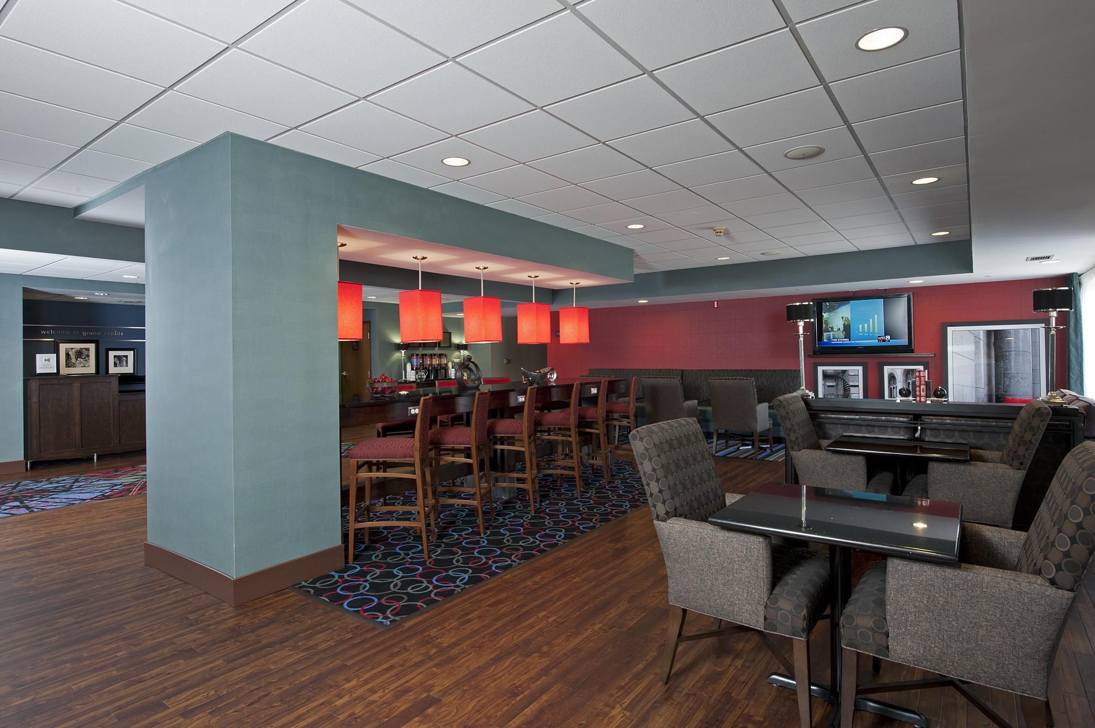 A hotel lobby with a bar area, seating, and a television screen.