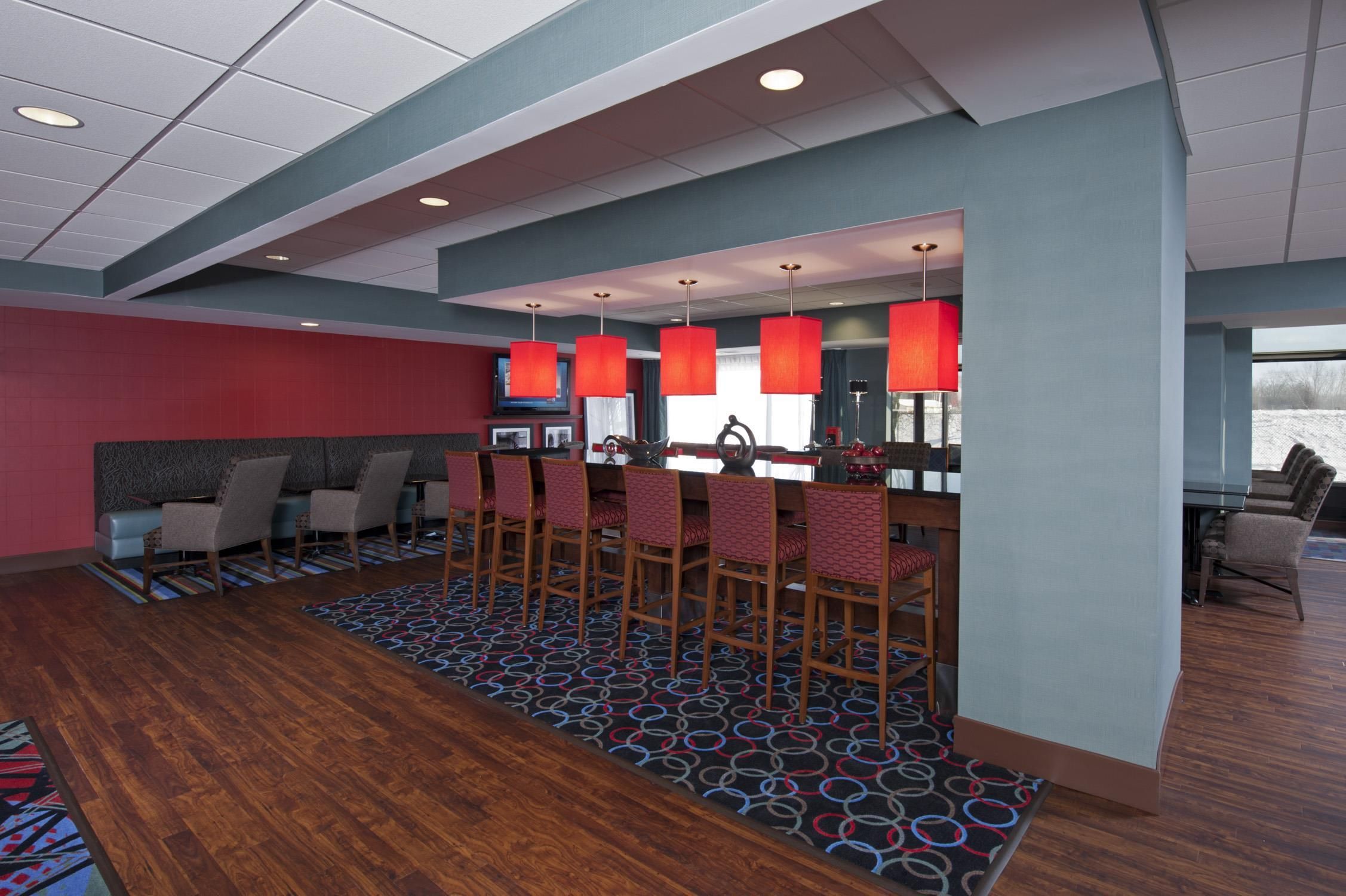 A modern hotel lobby with a bar area, seating, and a patterned carpet.