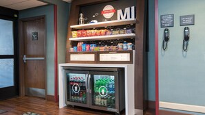 A vending machine with snacks and drinks, a lift receiver for guest assistance, and a door with a sign indicating the exit.