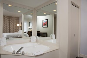 A hotel bathroom with a large mirror, a bathtub, and a bed visible in the reflection. - Hampton Inn Grand Rapids-South (Wyoming)