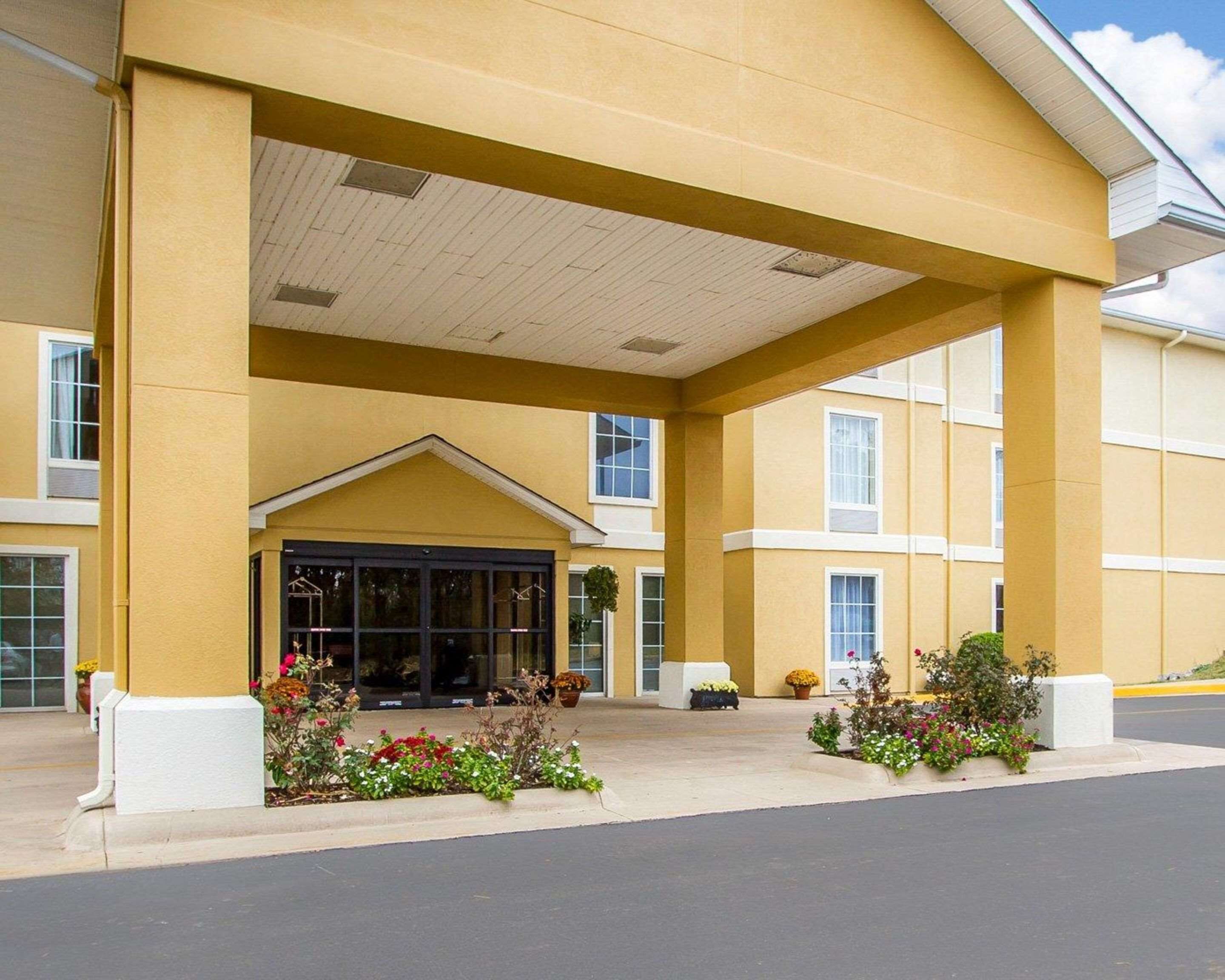 A hotel entrance with a covered walkway, large windows, and flower beds.