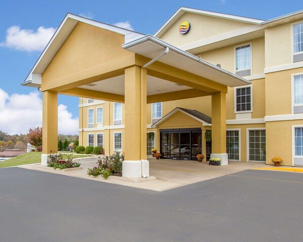 A hotel with a covered entrance, multiple windows, and a yellow facade.